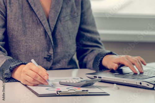 Close up of woman s hands working with financial data using calculator