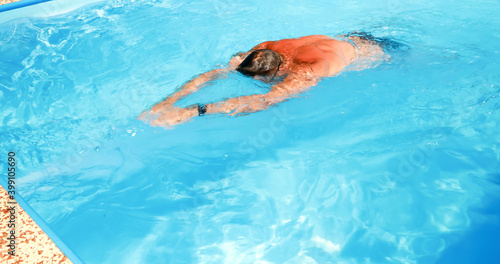 A young man trains in a home pool. Athlete swims in countercurrent. Fitness training as a healthy lifestyle.