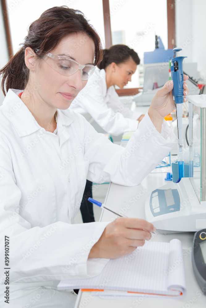 female researcher recording experiment in notebook female researcher recording experiment in notebook