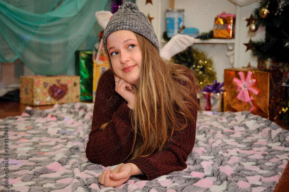 Fototapeta premium Beautiful girl on a Christmas background. Warm comfort in the house. Happy New Year. Christmas.