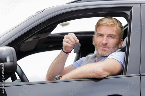 handsome man with the key standing in front of car