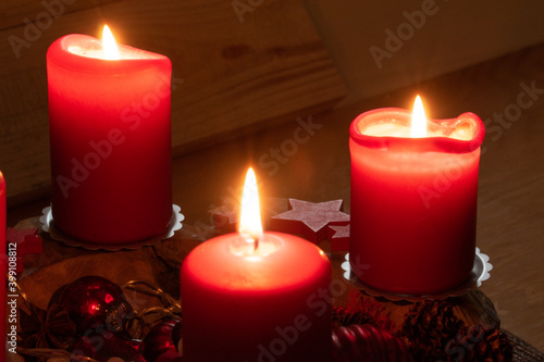 Rote brennende Kerzen auf einem Adventsgesteck. Es ist der dritte Advent. Bald ist Weihnachten.