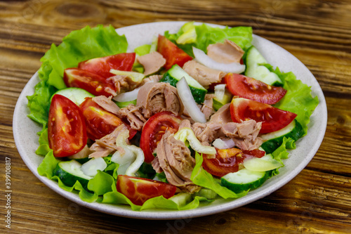 Tasty tuna salad with lettuce and fresh vegetables on wooden table