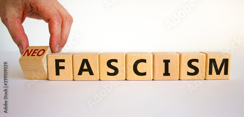 Neofascism symbol. Man hand turns a cube and changes the word fascism to neofascism. Business and fascism or neofascism concept. Beautiful white background, copy space. photo