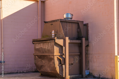 Small trash compactor and cardboard behind a grocery store