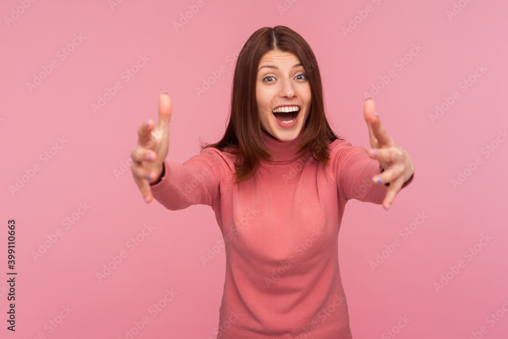 Friendly positive brunette woman in pink sweater stretching hands ready to cuddle looking at camera with happiness, free hugs. Indoor studio shot isolated on pink background Friendly positive brunette woman in pink sweater stretching hands ready to cuddle looking at camera with happiness, free hugs. Indoor studio shot isolated on pink background