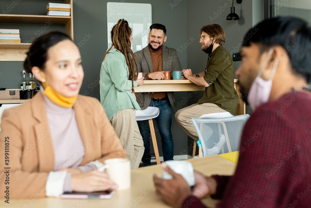 Group of intercultural happy office workers in casualwear having coffee at break Group of intercultural happy office workers in casualwear having coffee at break