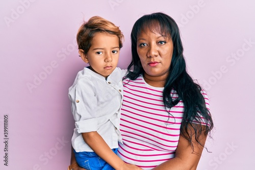 Fotografie Hispanic family of mother and son hugging together with love thinking attitude a