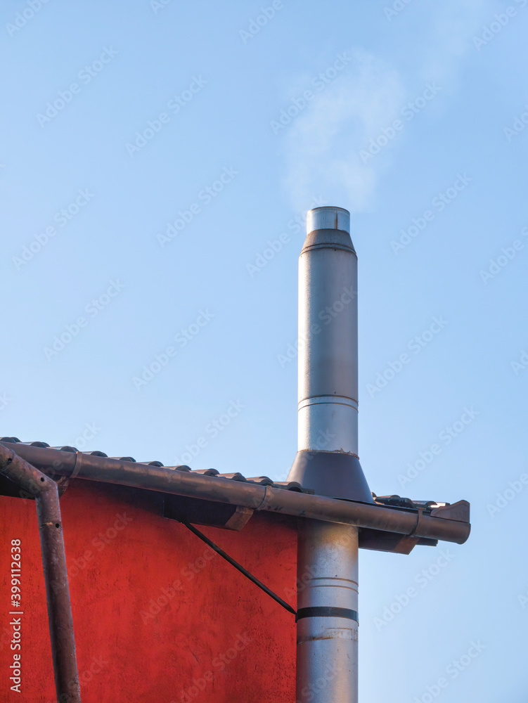 Metal tube pipe chimney on a house against blue sky. Metal tube pipe chimney on a house against blue sky.