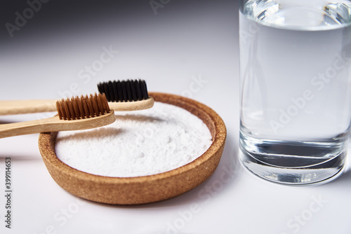 Bamboo toothbrushes, baking soda and glass of water on white background. Eco friendly toothbrushes, zero waste concept