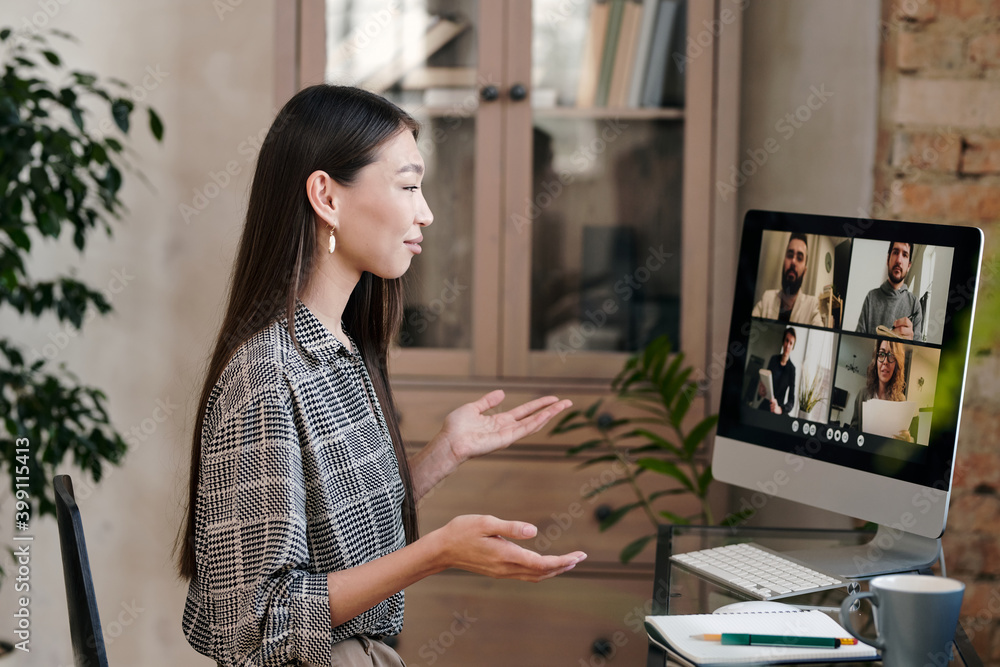 Confident and smiling young manager talking to colleagues on computer screen Confident and smiling young manager talking to colleagues on computer screen