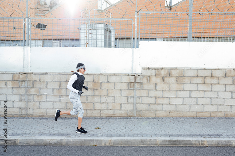 Sportswoman running around industrial zone in winter while sun rising. Sportswoman running around industrial zone in winter while sun rising.