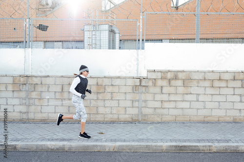 Sportswoman running around industrial zone in winter while sun rising.