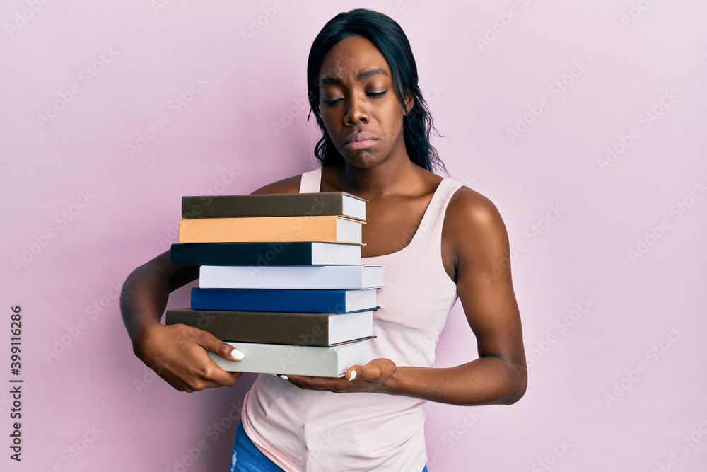 Young african american woman holding books depressed and worry for distress, crying angry and afraid. sad expression. Young african american woman holding books depressed and worry for distress, crying angry and afraid. sad expression.