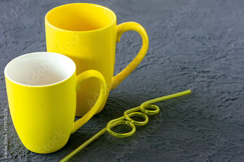 Two yellow cups on gray background. Color of the year 2021.