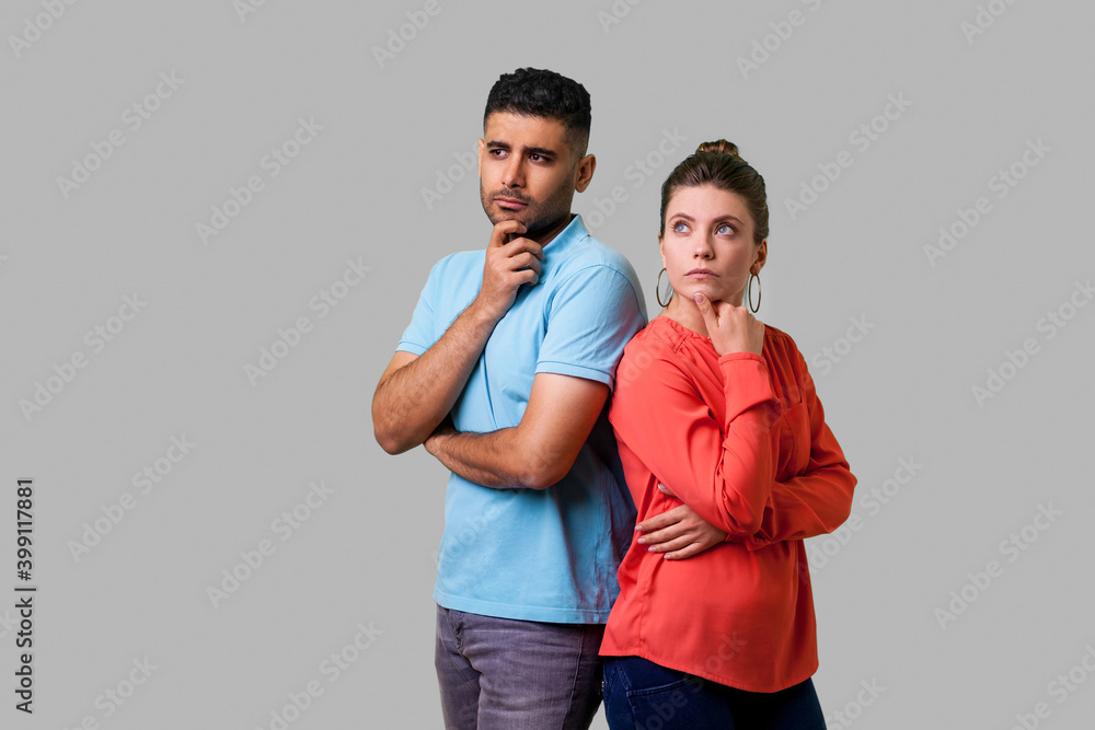 Think up plan! Portrait of smart attractive young couple in casual wear standing, holding their chins while thinking solution together, looking up. isolated on gray background, indoor studio shot Think up plan! Portrait of smart attractive young couple in casual wear standing, holding their chins while thinking solution together, looking up. isolated on gray background, indoor studio shot