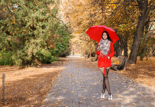 young girl in a red coat with an umbrella standing on the alley © Radnatt