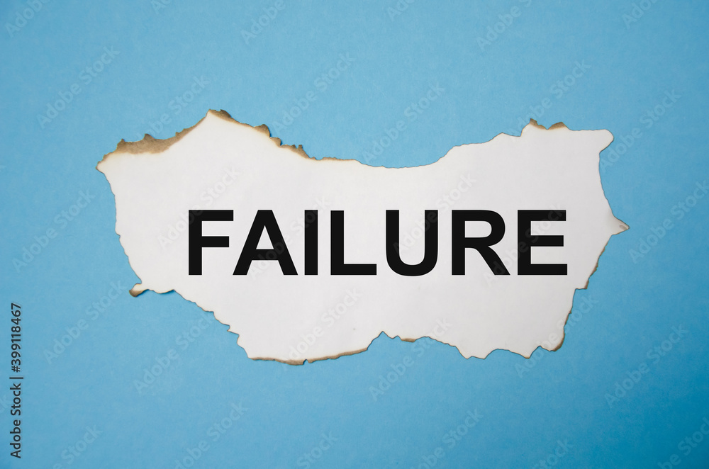 the word failure is written on a white sheet of paper that lies on a blue sticker