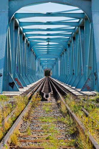 Blue steel railroad bridge with dual gauges at the national border between Sweden and Finland.
