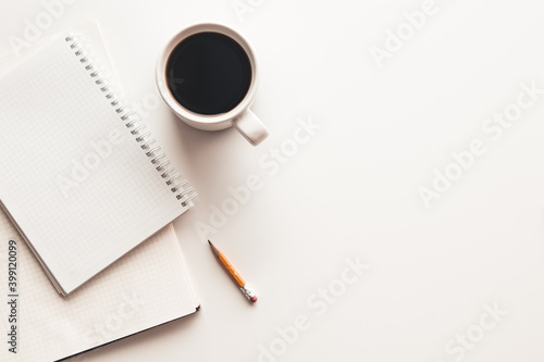 Office desk table with supplies, coffee cup and flower. Top view