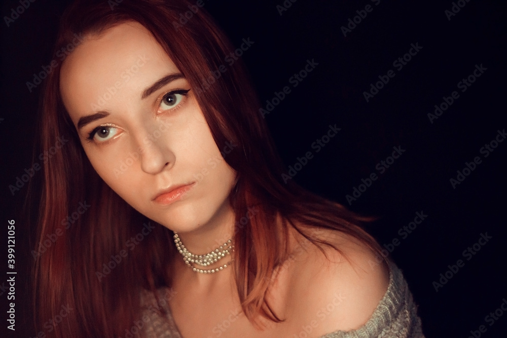 New Year's portrait of a girl in a sweater with a festive decoration-necklace on a black background New Year's portrait of a girl in a sweater with a festive decoration-necklace on a black background