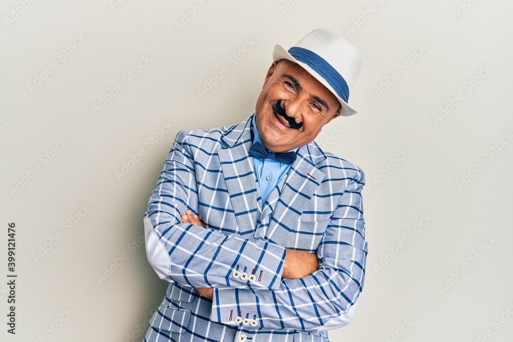 Mature middle east man with mustache wearing vintage and elegant fashion style happy face smiling with crossed arms looking at the camera. positive person.