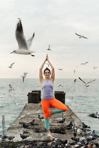 young woman doing yoga by the sea, seagulls flying around, meditation. High quality photo