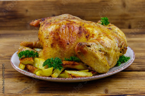 Baked whole chicken with potato on a wooden table