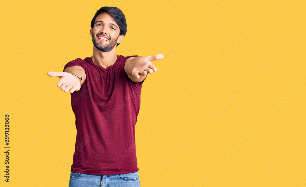 Handsome hispanic man wearing casual clothes looking at the camera smiling with open arms for hug. cheerful expression embracing happiness. Handsome hispanic man wearing casual clothes looking at the camera smiling with open arms for hug. cheerful expression embracing happiness.