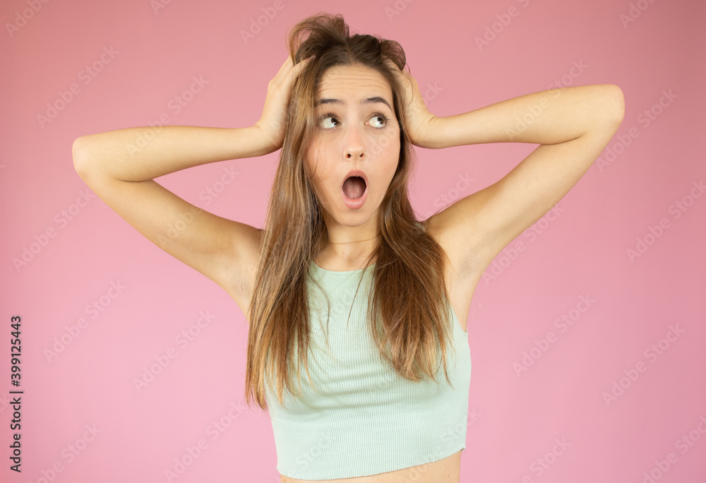 Young beautiful woman with straw hat feeling horrified and shocked, raising hands to head and panicking at a mistake against pink wall Young beautiful woman with straw hat feeling horrified and shocked, raising hands to head and panicking at a mistake against pink wall