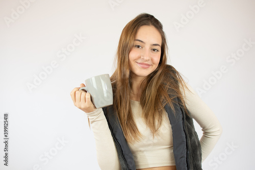 Portrait photo of nice cute girl holding cup of coffee showing at empty space smiling isolated on white color background