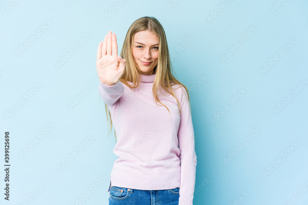 Fototapeta premium Young blonde woman isolated on blue background standing with outstretched hand showing stop sign, preventing you.