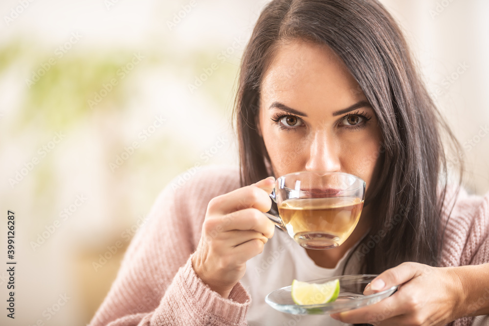 Tea drinking brunette woman having a cup of white, green or herbal tea in a glass cup Tea drinking brunette woman having a cup of white, green or herbal tea in a glass cup