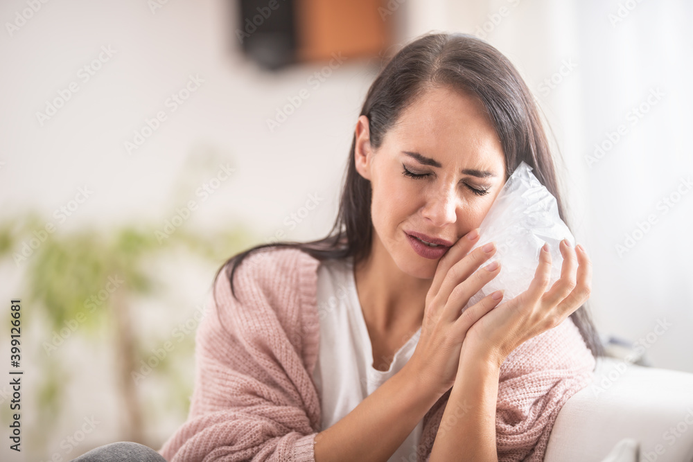 An effort of a girl to ease aching tooth by a bag of ice at home