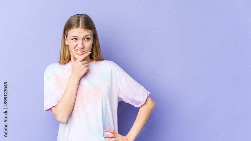 Young blonde woman isolated on purple background touching back of head, thinking and making a choice. Young blonde woman isolated on purple background touching back of head, thinking and making a choice.