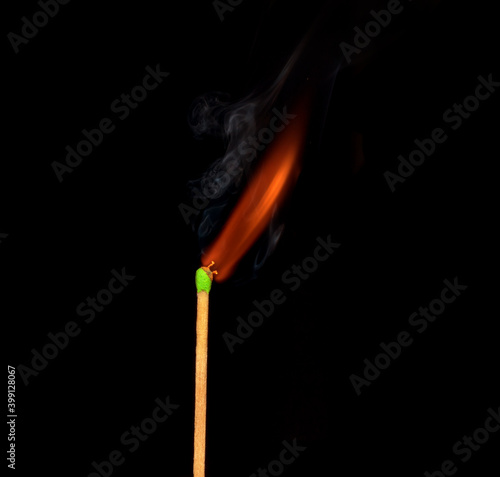 Ignition of match with smoke, isolated on black background. Match just after starting to burn.