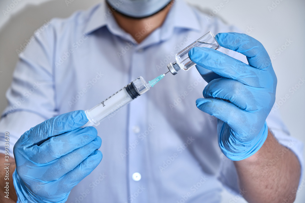 Pandemic concept, close up of scientist injecitng vaccine. Doctor, nurse, scientist hand in blue gloves holding flu, measles, coronavirus, covid-19 vaccine disease preparing for people.