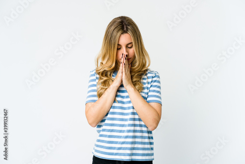 Young caucasian blonde woman praying, showing devotion, religious person looking for divine inspiration.