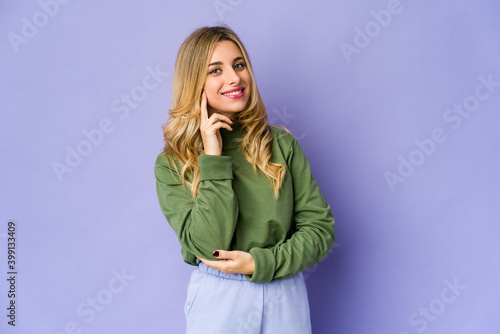 Young caucasian blonde woman smiling happy and confident, touching chin with hand.