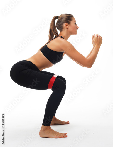 Strength and motivation. Sporty young woman squatting doing sit-ups with resistance band.
