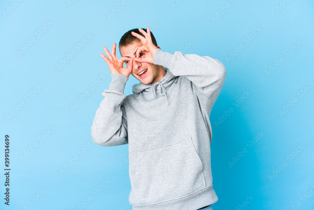 Young caucasian handsome man showing okay sign over eyes Young caucasian handsome man showing okay sign over eyes