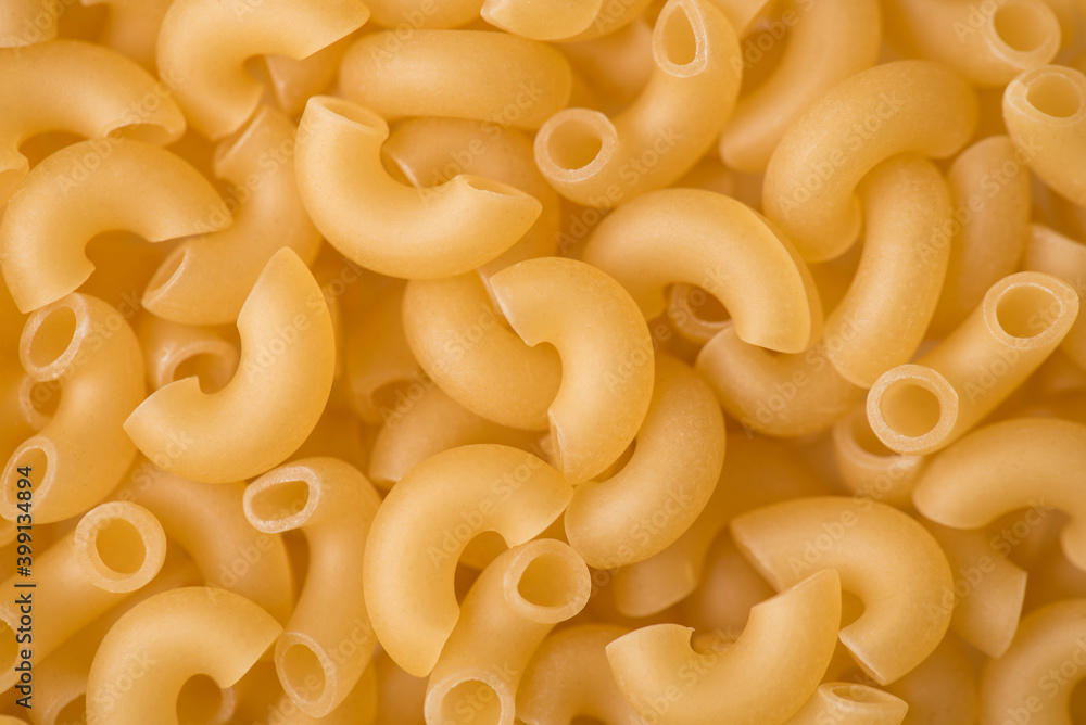Close up above top view photo of elbow shaped yellow uncooked macaroni textured background Close up above top view photo of elbow shaped yellow uncooked macaroni textured background