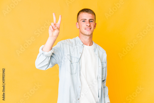 Young caucasian handsome man showing victory sign and smiling broadly.