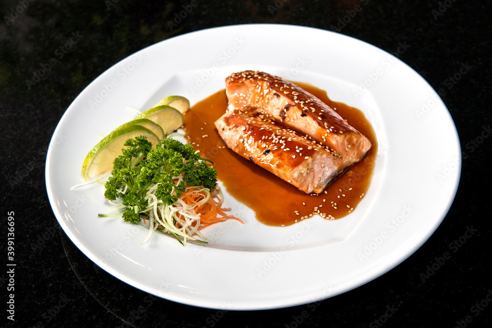 Grilled salmon teriyaki with vegetables and citrus Japanese food on white plate, on black background