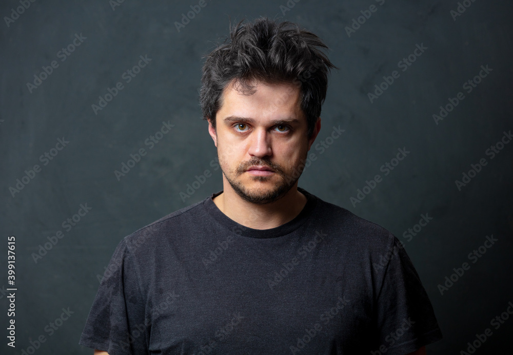 Tired brunet man in black t-shirt on dark background