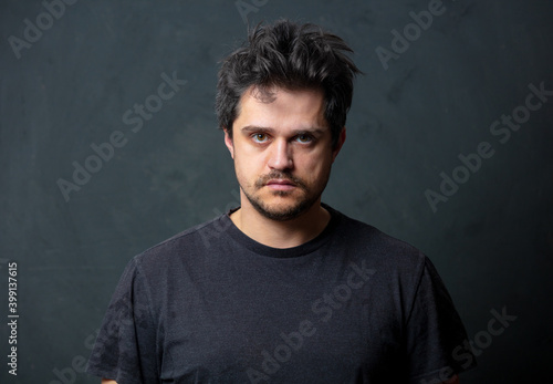 Tired brunet man in black t-shirt on dark background