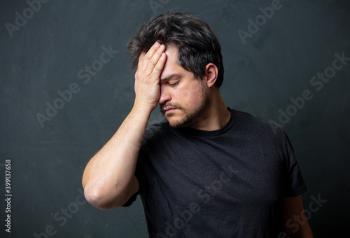 Tired brunet man in black t-shirt on dark background © Masson