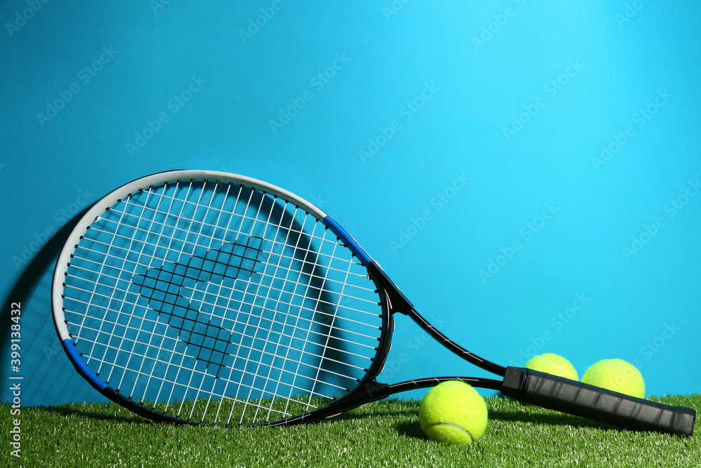 Tennis racket and balls on green grass against light blue background. Space for text