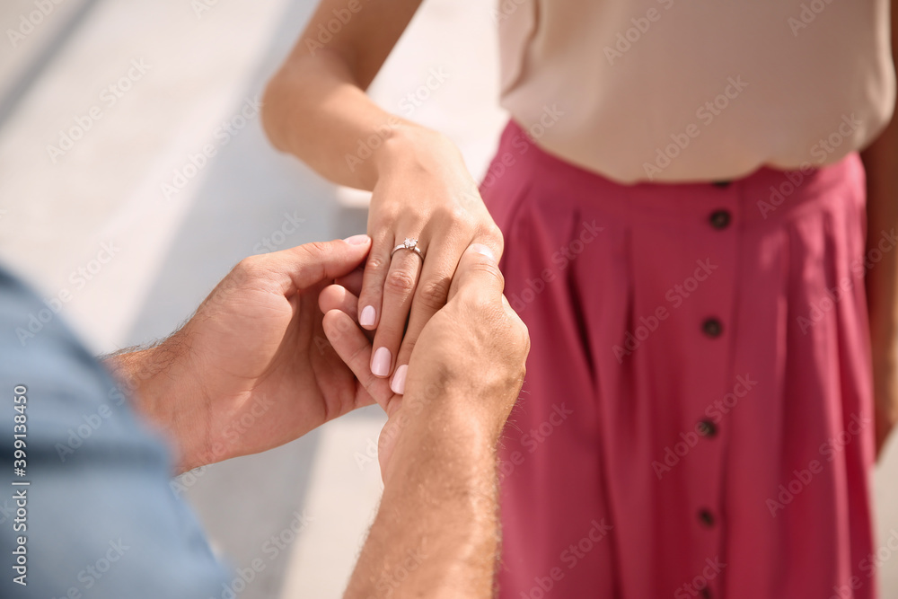 Fototapeta premium Lovely couple with beautiful ring after engagement outdoors, closeup