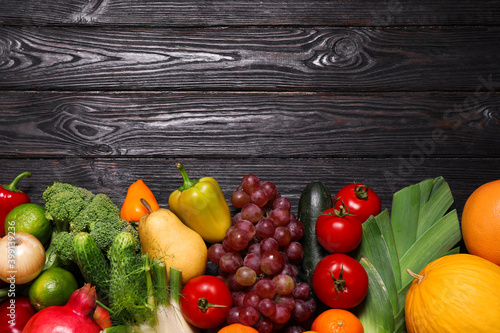 Assortment of fresh organic fruits and vegetables on black wooden table  flat lay. Space for text